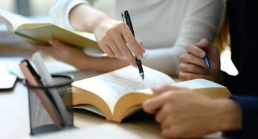 Close up of university students collaborating on studying material in library.