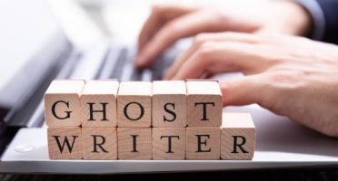 Ghostwriter Wooden Block On Computer Keyboard While Someone Typing