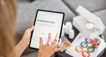 Woman checking the result of medical tests on a digital tablet, close-up with nutritional supplements on the background. Concept of individual online selection of food supplements