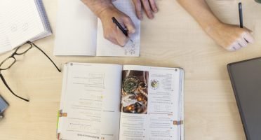 Teacher with schoolboy doing homework in classroom