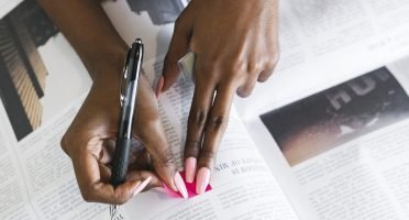 Black woman highlighting an article on the newspaper